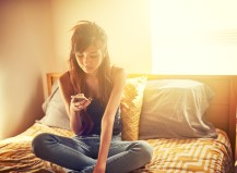 tech savvy asian teen girl using smart phone in bed room